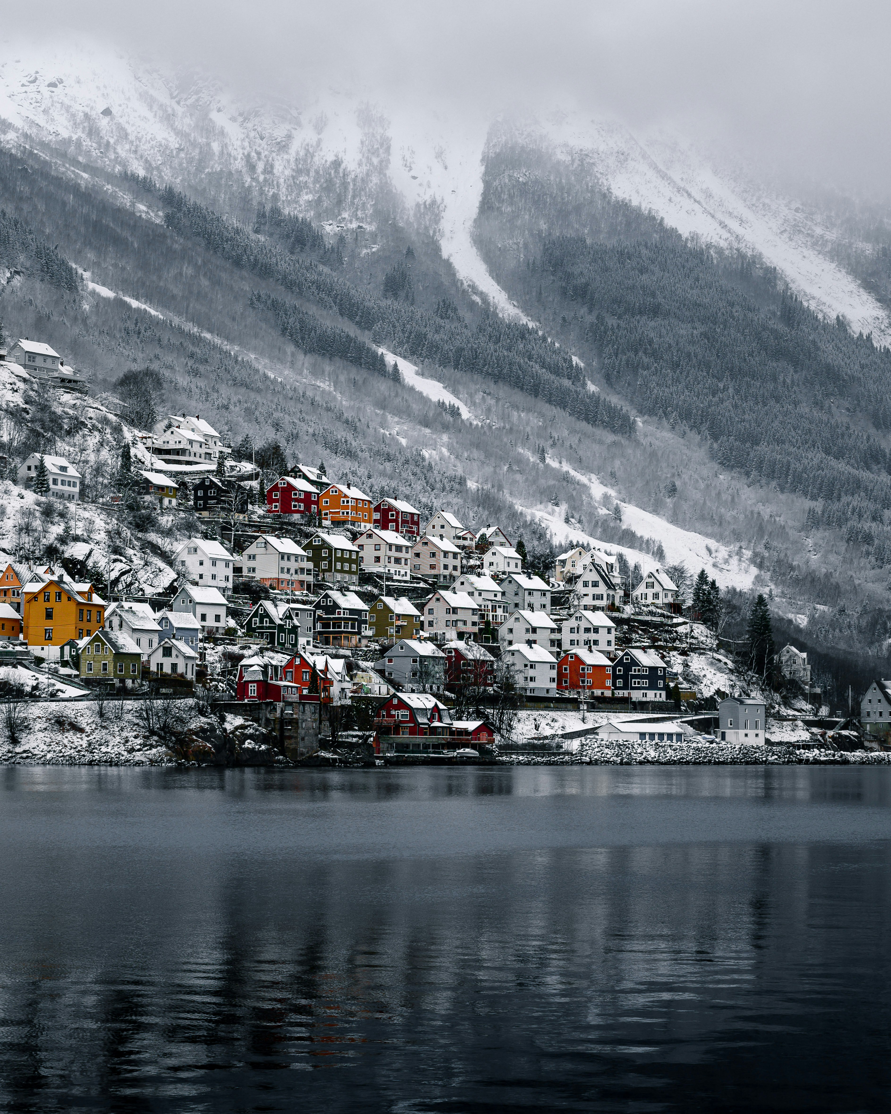 houses near body of water and snow covered mountain during daytime
